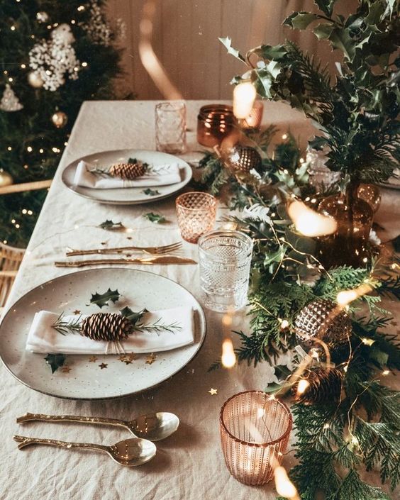 منظر طاولات عيد الميلاد المشرق مع عداء دائم الخضرة ، وأضواء ، وزخارف معدنية ، وألواح مطبوعة بنجوم ، وحوامل شموع نحاسية