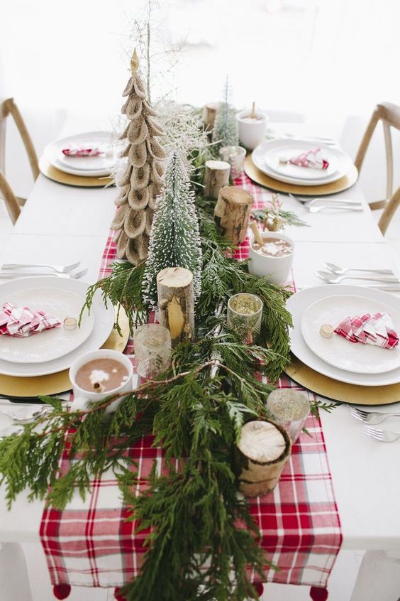 طاولة شتوية زاهية مع عداء أحمر منقوش ومناديل وفروع من خشب البتولا وأشجار عيد الميلاد المزيفة وعداء دائم الخضرة