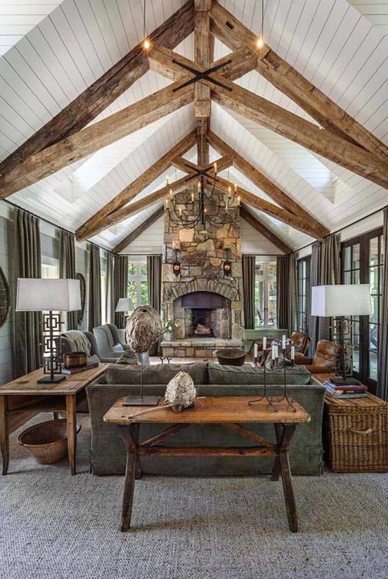 A Welcoming Barn Living Room With Wooden Beams A Fireplace Clad With Stone Grey Seating Furniture A Metal Chandelier And Baskets 