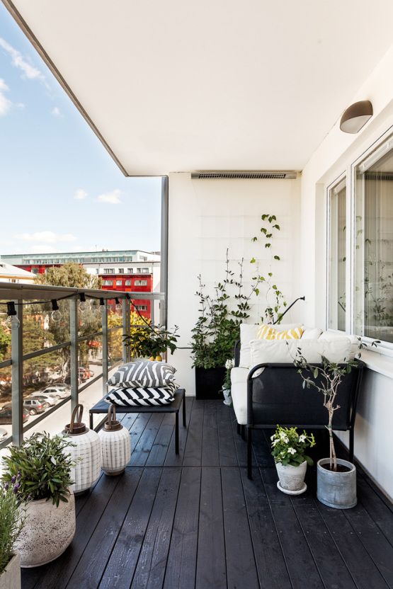 a-Nordic-balcony-with-a-black-floor-black-furniture-with-printed-and-neutral-upholstery-potted-blooms-and-candle-lanterns.jpg