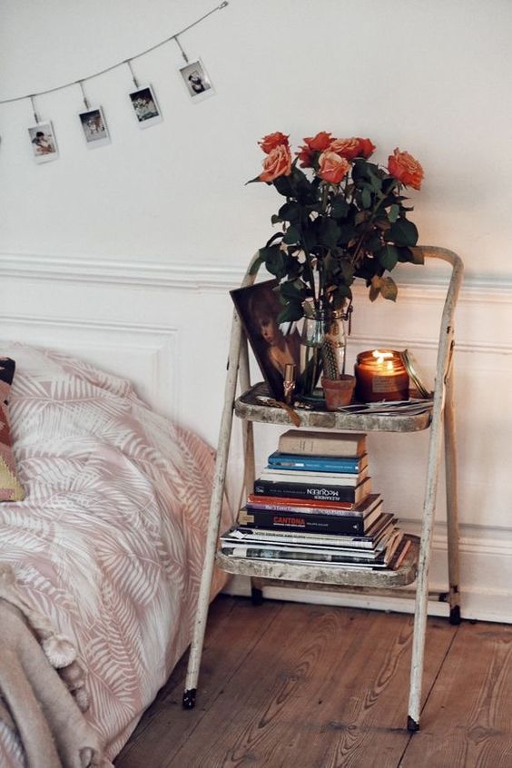 الدرج الأنيق المتهالك مع الكتب والشموع والأزهار هي لمسة جميلة ودقيقة لتصميم غرفة النوم التي يمكنك الحصول عليها مقابل بضعة دولارات