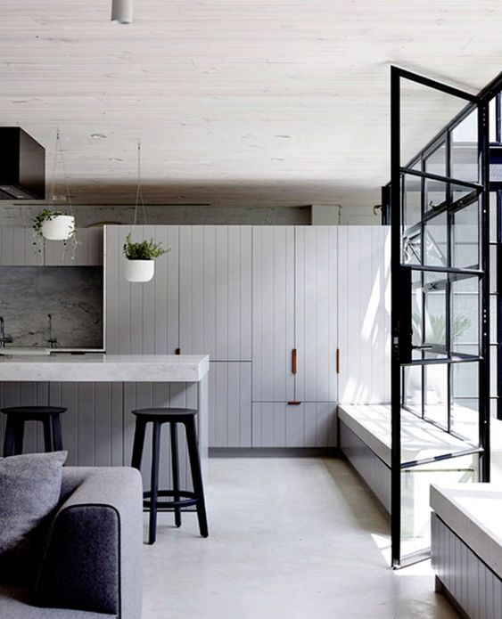 A Stylish Modern Kitchen With A Whitewashed Concrete Floor Grey Cabinets Grey Furniture And Potted Greenery 