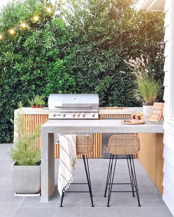 A Chic Contemporary Bbq Area Of Wood And Concrete With A Grill And A Cooking Zone A Concrete Dining Area And Rattan Stools 
