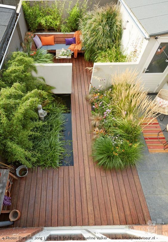 A Minimalist Townhouse Garden With A Wooden Deck A Pond Planted Herbs And Grasses And A Built In Bench 