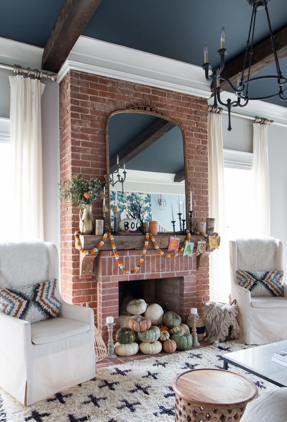 a natural pumpkin stack in the fireplace decorated with fall-colored garlanfs and greenery