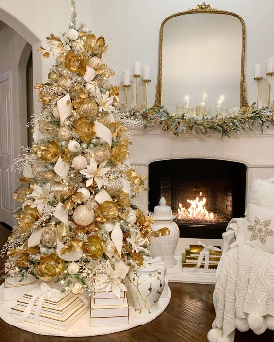 شجرة عيد الميلاد الجميلة مغطاة بالكامل بزخارف بيضاء وذهبية وأزهار بيضاء وذهبية وفروع جليدية وذهبية
