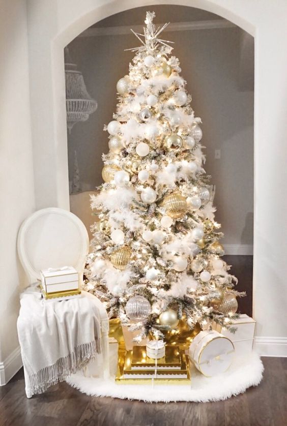 شجرة عيد الميلاد المكررة والرائعة مع الحلي البيضاء والفضية بالإضافة إلى الزخارف الذهبية الضخمة والأضواء والغطاء النجمي