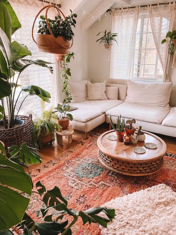 https://www.digsdigs.com/photos/2015/01/a-very-cozy-boho-sunroom-with-a-white-sectional-a-wooden-carved-table-lots-of-potted-greenery-layered-rugs-and-macrame-curtains.jpg