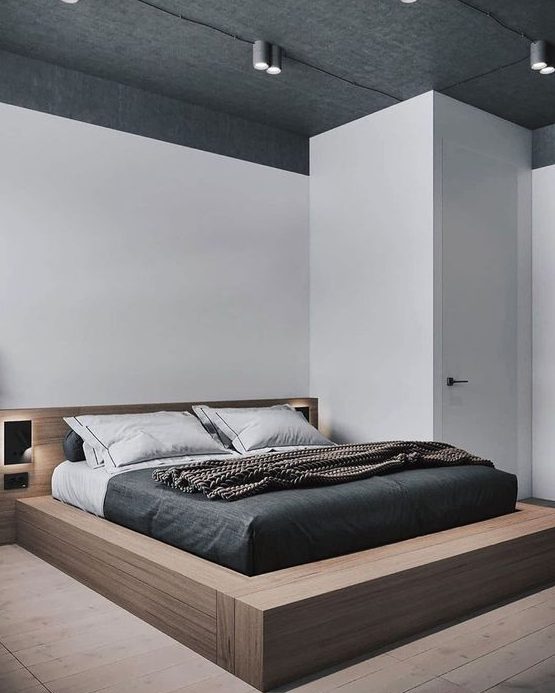 غرفة نوم أنيقة بسيطة مع سرير من الخشب الرقائقي مع أضواء مدمجة وأضواء على السقف وفراش أحادي اللون