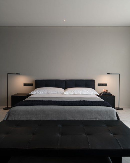 غرفة نوم متناقضة بسيطة مع سرير أسود منجد ومقعد جلدي أسود وطاولات جانبية سوداء ومصابيح