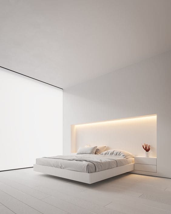 غرفة نوم بيضاء بسيطة بجدار زجاجي مغطى بستارة ، وسرير مدمج مع أضواء فوقه ، وطاولات جانبية مدمجة