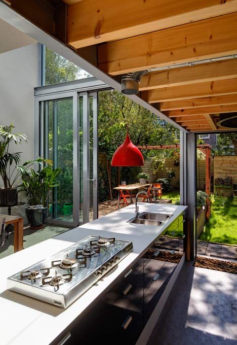 https://www.digsdigs.com/photos/2015/06/a-modern-black-kitchen-with-glossy-cabinets-a-red-pendant-lamp-and-a-glass-wall-with-sliding-doors-to-connect-to-the-garden.jpg