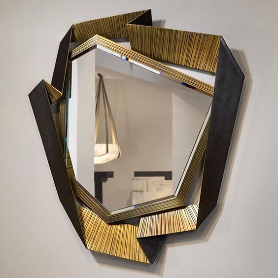 a uniquely shaped geometric mirror of an asymmetrical shape and a gold and black geo frame is amazing as an artwork