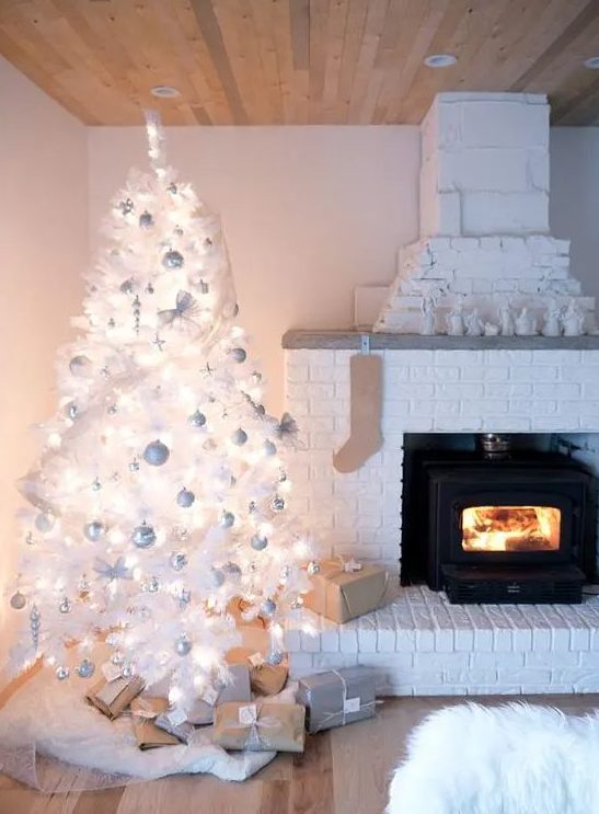 white Christmas tree with lots of ornaments oversized snowflakes, pinecones  and a chic…