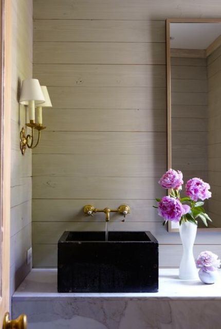 taupe plank walls, a marble surfce and a black sink