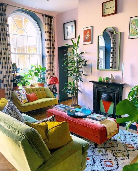 a bright maximalist living room with pink walls, mustard and neon green furniture, a vintage fireplace, a red ottoman and some statement plants