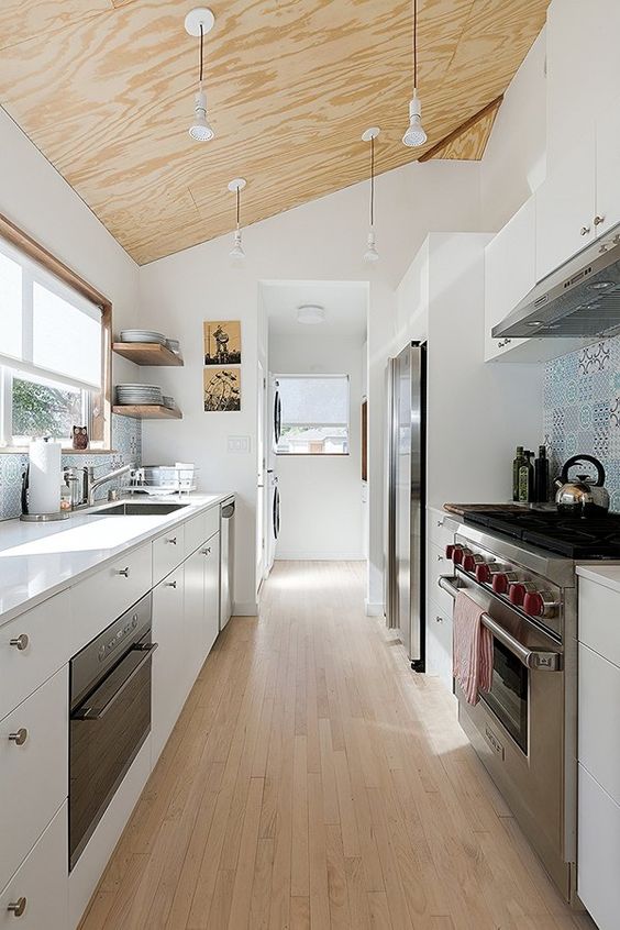 A Contemporary White Galley Kitchen With A Plywood Ceiling With Penddant Lamps A Wooden Floor And A Blue Tile Backsplash 