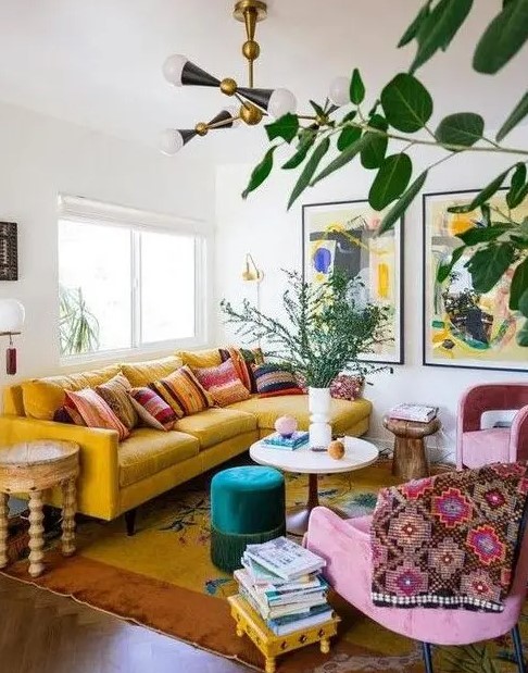 a maximalist living room with a yellow sofa, pink chairs, various tables and bold artworks plus potted plants