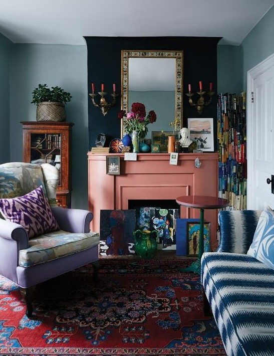 a maximalist living room with green walls, a lilac chair and a blue and white sofa, colorful pillows, a coral fireplace and bright accessories