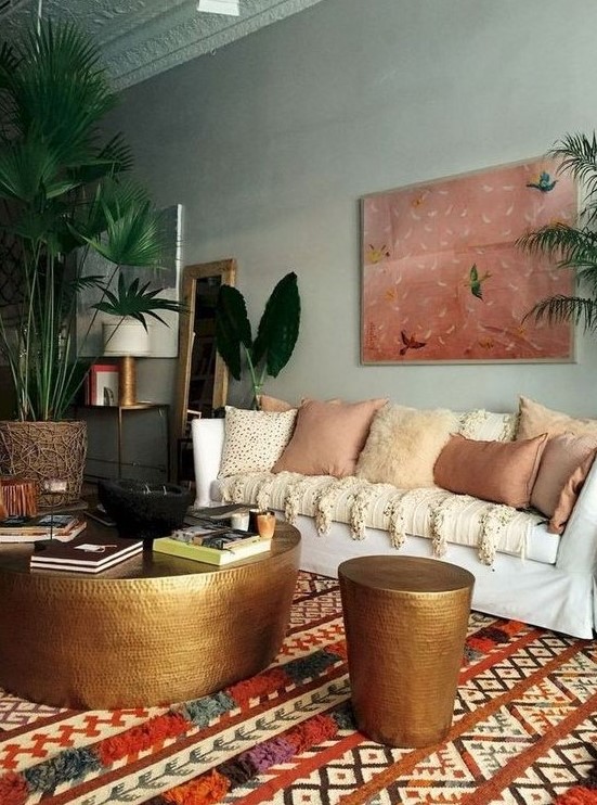 a moody eclectic space with a statement artwork, a boho printed rug, lots of earthy pillows and metal hammered items