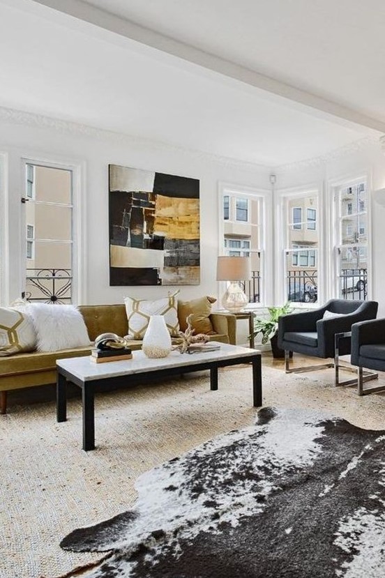 an eclectic light-filled living room with graphite grey chairs, a faux animl skin, a statement artwork and a mustard velvet sofa