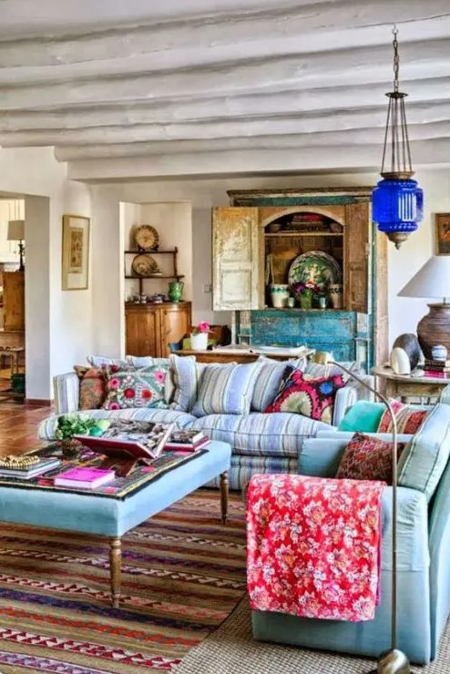 an ethnic maximalist living room with pastel blue seating furniture, a turquoise buffet, a Moroccan lamp and bold ethnic textiles