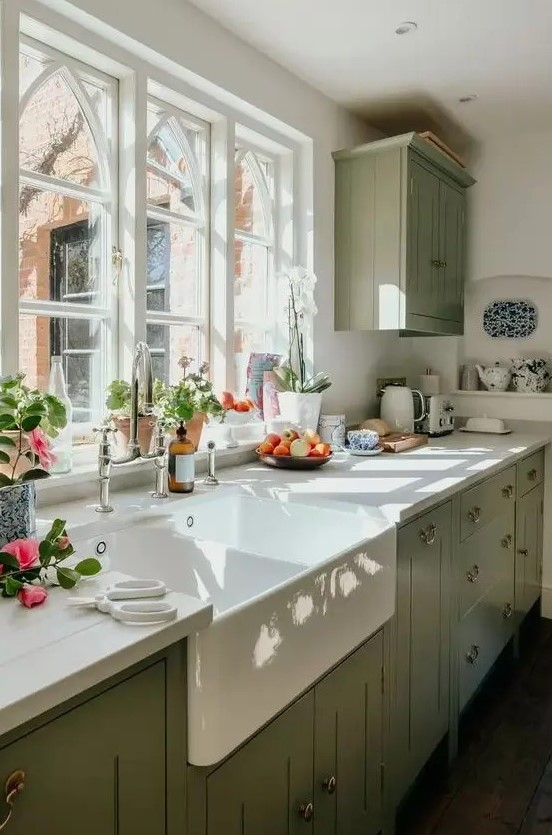 https://www.digsdigs.com/photos/2020/03/a-sage-green-farmhouse-kitchen-with-white-stone-countertops-a-single-upper-cabinet-vintage-fixtures-and-a-vintage-sink.jpg