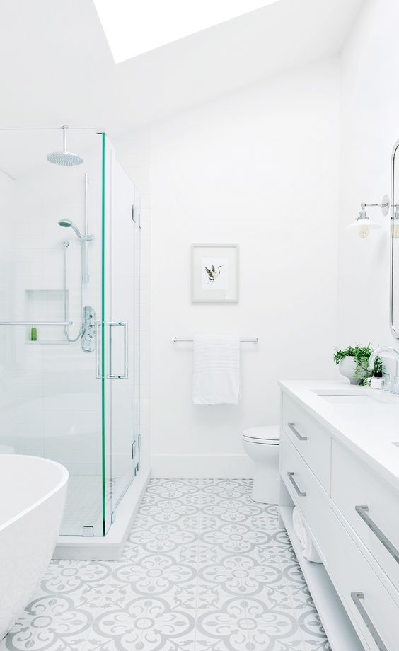 بالصور ديكورات حمامات انيقة باللون الابيض لمنزلك في ربيع 2020 حصري A-beautiful-white-bathroom-with-a-glass-enclosed-shower-space-a-large-vanity-a-mosaic-tile-on-the-floor-and-a-large-skylight