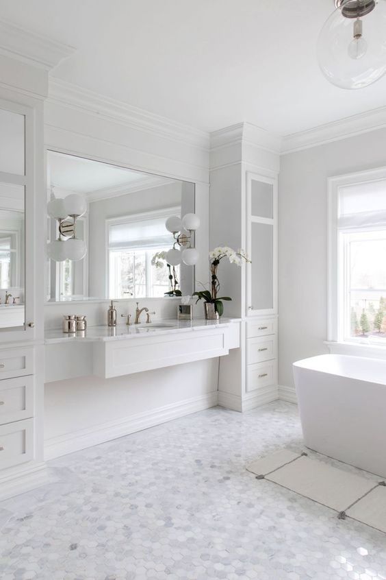 بالصور ديكورات حمامات انيقة باللون الابيض لمنزلك في ربيع 2020 حصري A-chic-and-stylish-white-bathroom-with-marble-hex-tiles-on-the-floor-a-tub-a-vanity-with-storage-units-and-a-mirror