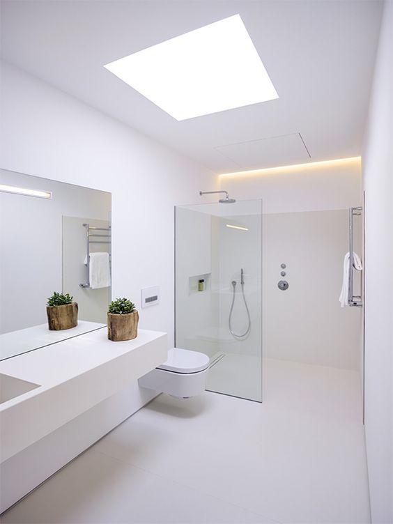 بالصور ديكورات حمامات انيقة باللون الابيض لمنزلك في ربيع 2020 حصري A-minimalist-white-bathroom-with-a-skylight-a-floating-vanity-a-seamless-glass-shower-space-and-built-in-lights