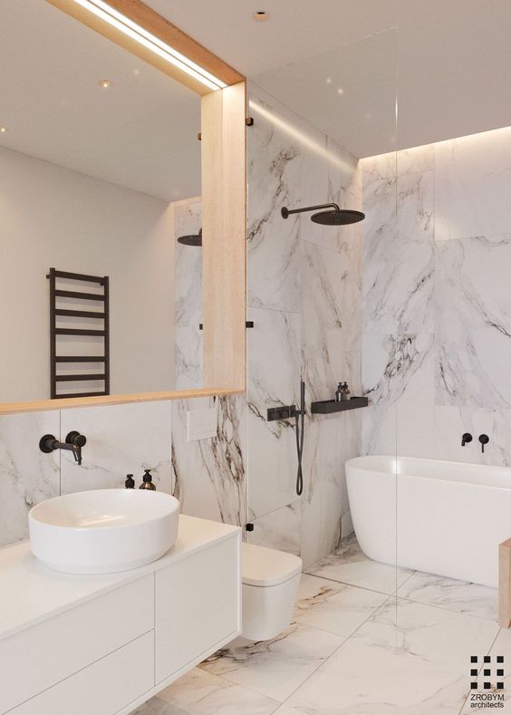 بالصور ديكورات حمامات انيقة باللون الابيض لمنزلك في ربيع 2020 حصري A-refined-white-bathroom-done-with-large-scale-marble-tiles-with-black-fixtures-and-a-large-mirror-in-a-wooden-frame