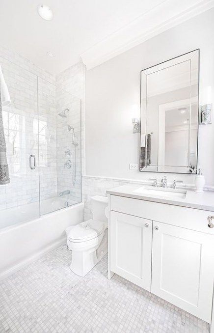 بالصور ديكورات حمامات انيقة باللون الابيض لمنزلك في ربيع 2020 حصري A-traditional-chic-white-bathroom-with-marble-tiles-a-tub-and-shower-combo-with-a-vanity-and-a-large-mirror