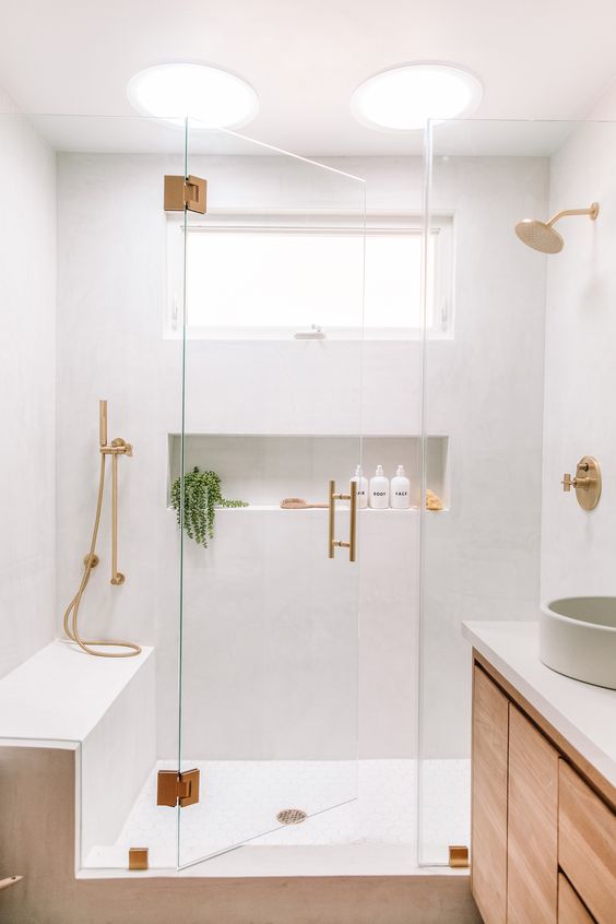 https://www.digsdigs.com/photos/2020/05/a-lovely-neutral-bathroom-with-white-walls-a-stained-vanity-a-bench-and-a-niche-in-the-shower-gold-fixtures.jpg