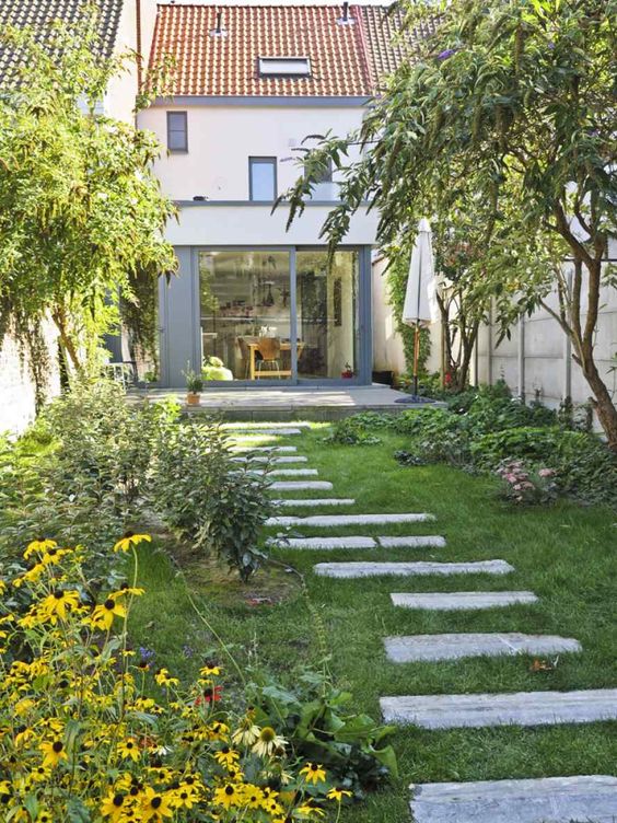 بالصور افكار بسيطة مميزة لتزيين حديقة المنزل حصري 2020 A-small-backyard-gardem-with-a-green-lawn-greenery-and-bright-blooms-and-some-trees-plus-a-pavement