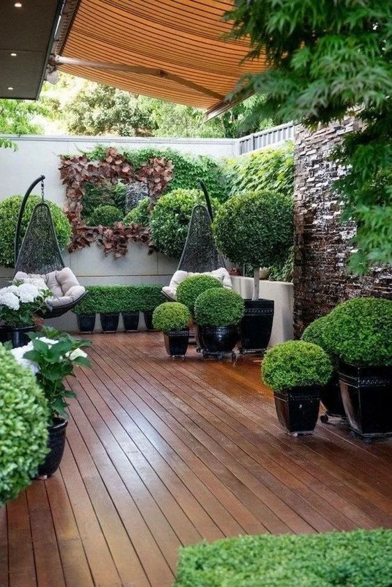 بالصور افكار بسيطة مميزة لتزيين حديقة المنزل حصري 2020 A-small-contemporary-garden-with-lots-of-greenery-in-planters-some-shrubs-greenery-on-the-walls-and-suspended-chairs