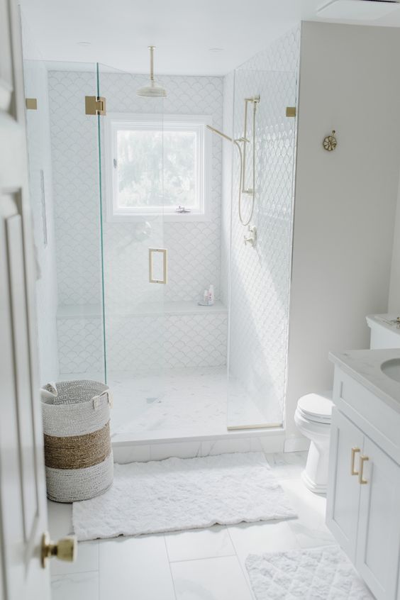 https://www.digsdigs.com/photos/2020/05/a-small-white-bathroom-with-large-scale-and-fish-scale-tiles-a-shower-space-a-white-vanity-and-a-basket-plus-gold-fixtures.jpg