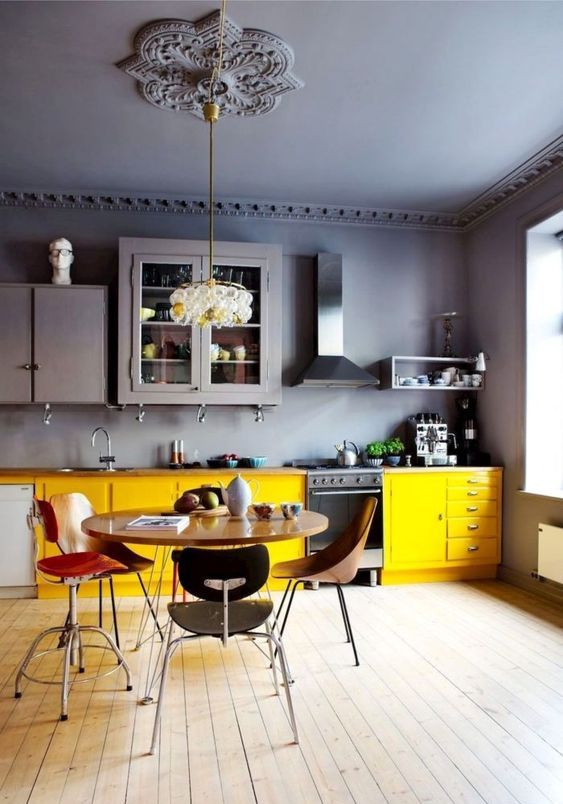 Dark grey gloss kitchen with small seating area and yellow accessories.