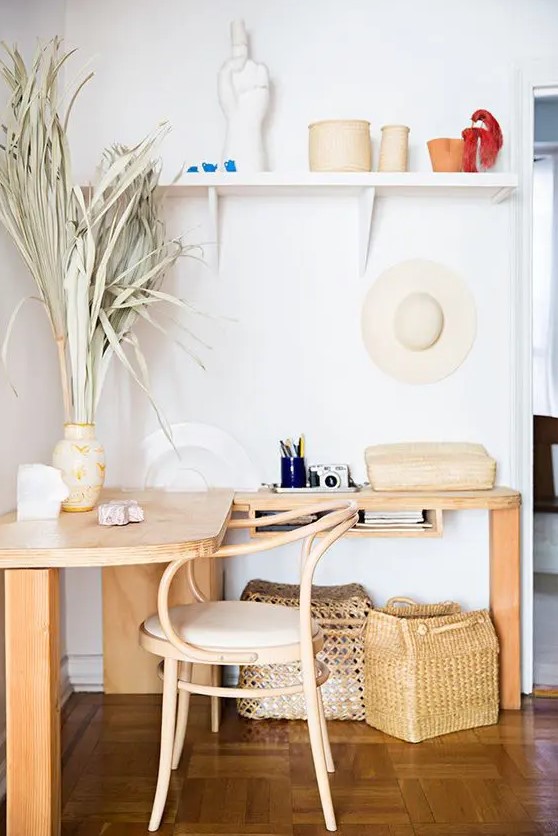 an awkward nook styled as a boho working space with a corner desk, with a wooden chair, an open shelf, some grass, baskets and vases