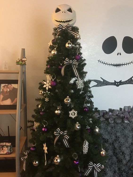 A Christmas tree adorned with purple and gold decorations and bows, along with Jack Skellington ornaments for added style and sophistication.