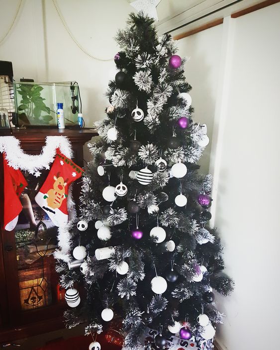 Decorating with a stunning contrast, the Jack Skellington themed decorations, along with white and purple embellishments, complement the exquisite flocked black Christmas tree.