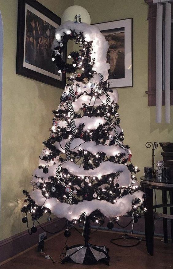 A ebony Christmas tree with ebony and ivory ornaments, ivory cotton snow, a twirled top and striped ribbons.