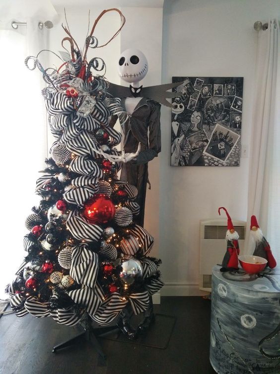 A dark Christmas tree with patterned ribbons, golden, silver, crimson and dark decorations and a Jack Skellington statue beside it.