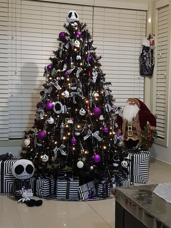 A dark Halloween tree adorned with lights, Jack Skellington decorations, purple ones, and a few striped bows.
