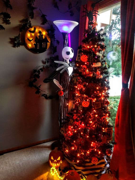 A stunning ebony Christmas tree adorned with orange lights, pumpkins, Nightmare Before Christmas decorations, and a Jack Skellington statue adjacent to it.