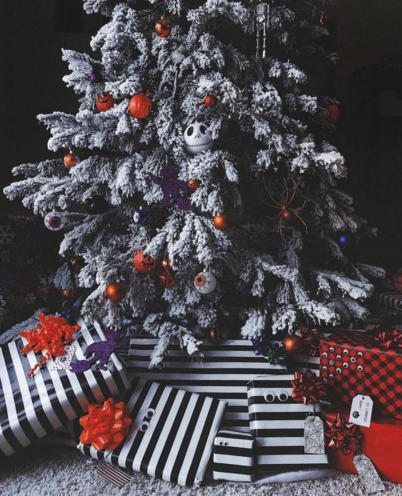 A beautiful decorated Christmas tree with eyeball, pumpkin and Jack Skellington ornaments and lights, along with striped presents underneath it.