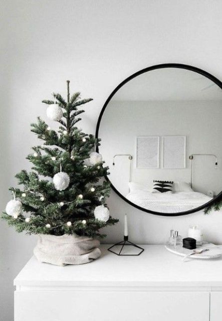 a small and simple tabletop Christmas tree with pompom garlands and large pompom ornaments for a Nordic feel