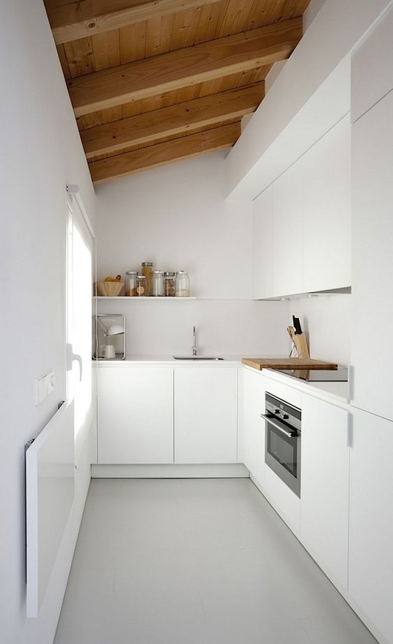 مطبخ أبيض أنيق للغاية مع غطاء مدمج وأسطح عمل وغطاء خلفي بالإضافة إلى سقف وعوارض خشبية