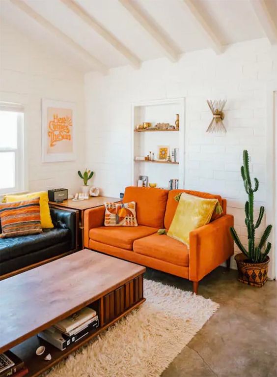 A Boho Living Room With A Black Leather Sofa An Orange Loveseat A Low Table And Potted Cacti Feels Warm And Cool 