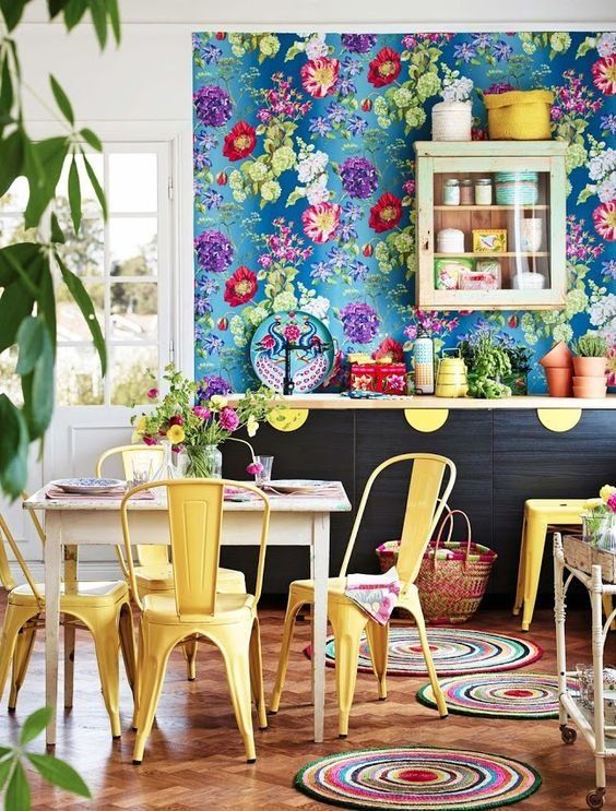مطبخ بسيط بجدار زهري أزرق وخزائن داكنة ولمسات صفراء وسجاد ملون ونباتات أصص