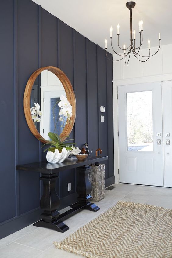 28 Stylish Navy Accent Walls For A Dramatic Accent DigsDigs   An Elegant Coastal Farmhouse Entryway With A Navy Paneled Wall A Tiled Floor A Black Console Table A Round Mirror In A Wooden Frame And A Vintage Chandelier 